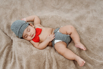 3-month-old Asian newborn in a knitted sweater is happily sleeping warmly on the rug in the bedroom. Concept Happy Family - obrazy, fototapety, plakaty