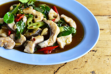 Close up Stir-fried fish (Hemibagrus wyckioides) with herbs and spices on wooden table. Authentic Thai food.