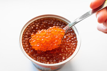 a spoonful of salted red caviar is taken out of the jar. delicacy. delicious canned fish. a traditional Russian snack for a festive banquet.