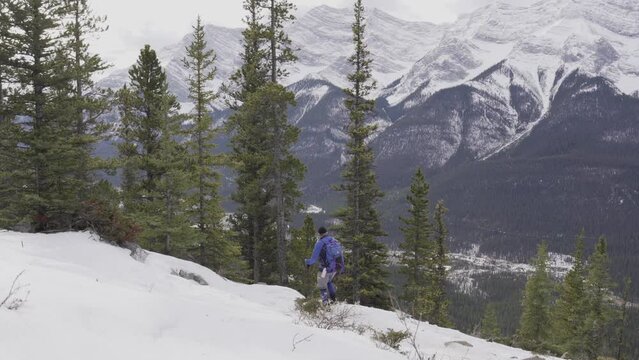 Canmore Alberta Canada, December 10 2018: Tracking shot of a hiker descending an alpine trail wearing a backpack in the Canadian Rocky mountains near Banff Canada.