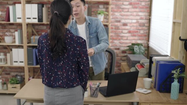 asian manager is laughing while having a meeting with a potential business partner who just handing over a visiting card in a loft office.