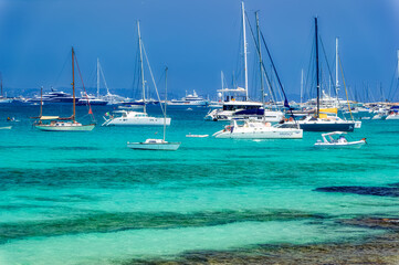 Obraz premium Yachts anchored at turquoise lagoon during summer day at island of Formentera, Spain.