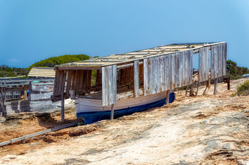 Fototapeta na wymiar Traditional way of keeping small fishing boats under old wooden shad while on land in Formentera, Spain.