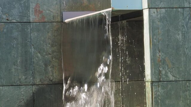 Modern artificial waterfall fountain on green granite wall in Ourense