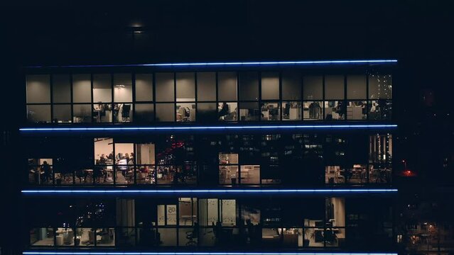 People work in Offices in a large modern business center with transparent panoramic windows. Call center managers in offices work around the clock at night. People work in modern Glass coworking.