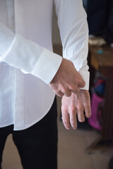 A man arranges the shirt , A man in a white shirt, a man getting dressed, a man's hand