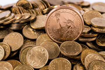A pile of coins in denominations of 1 Kazakh tenge and 1 American dollar