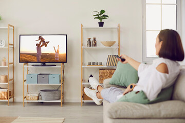 Woman renter relax on comfortable couch in modern home watch TV program, use good mobile provider...