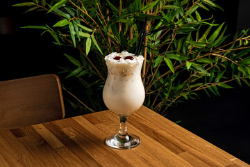 Pina colada cocktail in a hurricane glass, garnished with cherries and a straw - 491766744