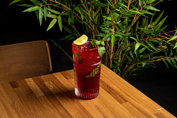 Cherry lemonade in a highball collins glass garnished with berries, lime and mint leaves © jamurka
