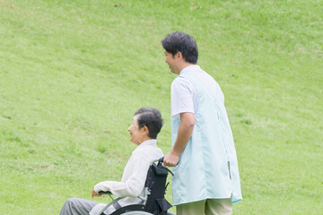 車椅子に乗った高齢者と介護士　屋外