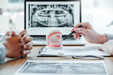 Dentist with male patient presenting discussing dental problems x-ray image film in dental office