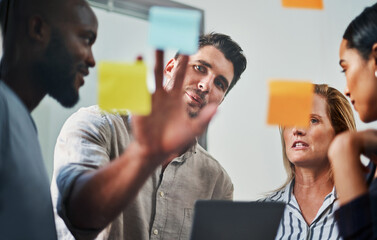 Success is a joint effort. Cropped shot of a group of business colleagues brainstorming on a glass wipe board in their office.