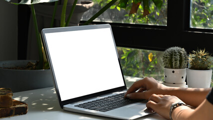 Close up view young woman sitting near window at home office and using computer laptop.