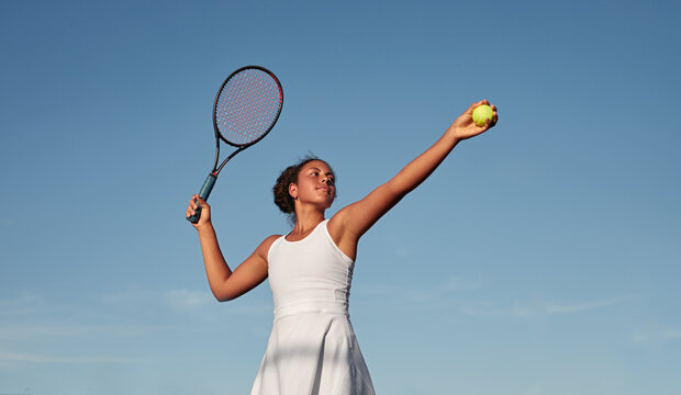 Black sportswoman playing tennis against blue sky