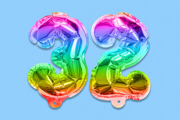 Rainbow foil balloon number, digit thirty two on a blue background. Birthday greeting card with inscription 32. Top view. Numerical digit. Celebration event, template.