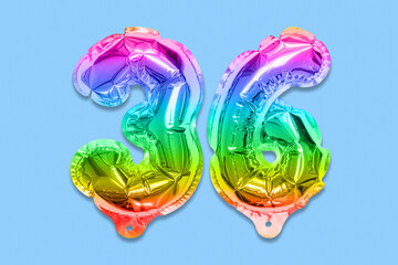 Rainbow foil balloon number, digit thirty six on a blue background. Birthday greeting card with inscription 36. Top view. Numerical digit. Celebration event, template.