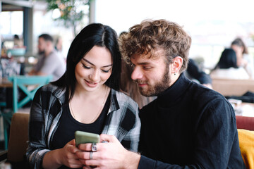 couple in a cafe looking at a cellphone