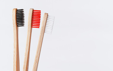 Red, white and black bamboo toothbrushes on white background. Copy space, close up.