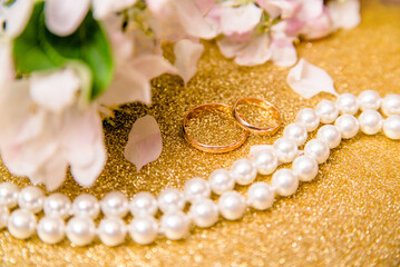 Gold wedding rings and Apple blossoms on a Golden background
