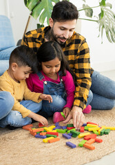 Hispanic father playing with his little children on carpet at home