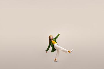 Full length view of dancing caucasian young brunette lady having fun on white studio background. Refined french woman wears beret, jacket and pants. Stylish woman having good time.