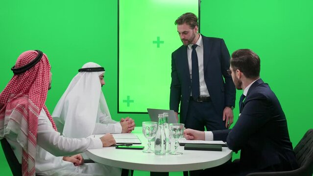 International business meeting, a man speaker communicate with a arab business partners in a white kanduras, discussing investments for projects, chroma key template.