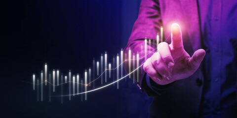 Close up of hand pointing at glowing business chart on dark blue backdrop. Stock, market and trade...