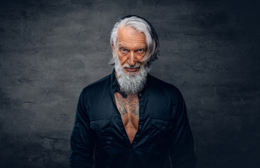 Handsome elderly man dressed in black shirt against dark background