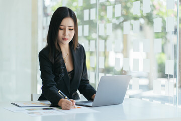 Attractive Asian woman working with laptop in her office.