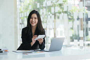 Portrait of asian business woman paying bills online with laptop in office. Beautiful girl with...