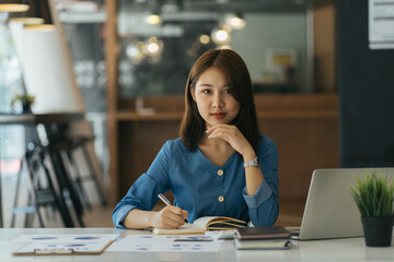 Attractive young brunette asian woman using laptop computer while sitting in a stylish living room.