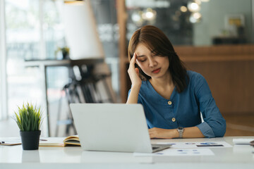 Fototapeta na wymiar Stressed young woman doing paperwork at modern workplace. Stress concept