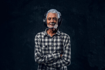 Contemporary grandpa with headphones dressed in plaid shirt