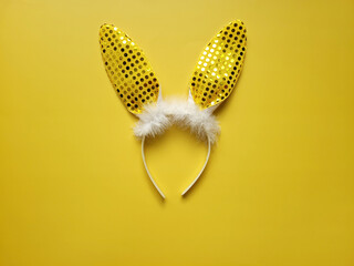 Flat lay accessory costume bunny ears on beautiful yellow background at home office desk. Coffee cup. Creative concept of happy Easter holiday. 