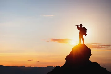 Fotobehang vision for success ideas. businessman's perspective for future planning. Silhouette of man holding binoculars on mountain peak against bright sunlight sky background. © Midnight Studio