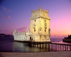 Tower of Belem illuminated against a pink and purple sunset, Lisbon, Portugal.