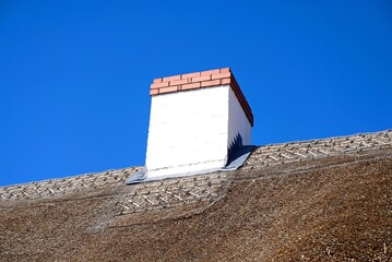 White chimney atop a thatched cottage roof, Kings Bromley, Staffordshire, UK.