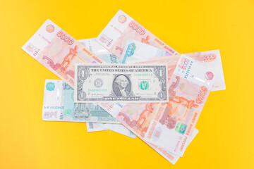 Scattered Russian money of various denominations on a yellow background and one American dollar on top: the economic crisis, the exchange rate