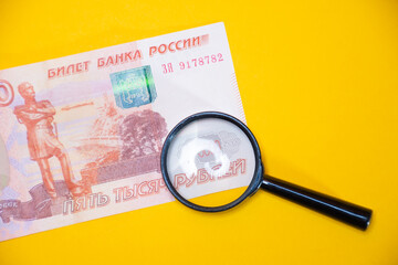 Ivanovo, Russia - 03.03.2022: Magnifying glass on money and paper bills of Russia: crisis, exchange...
