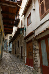 Traditional stone built houses around empty cobblestone pavement. Day view of historic Dimitsana village narrow alleys without crowd, in Arcadia Peloponnese.