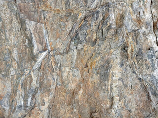 Stone mountains natural material background. Empty rough, uneven texture of a brown and gray concrete wall close up with copy space.