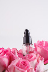 Bottle of facial serum on stone with rose flower on gray background, copy space