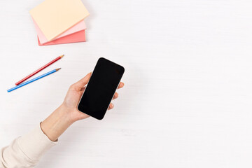woman holding phone at work desk