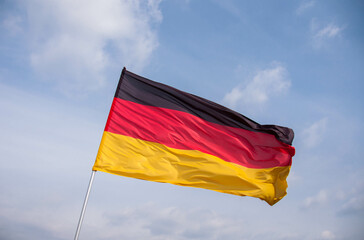Germany flag waving in the wind close-up against a blue sky. 