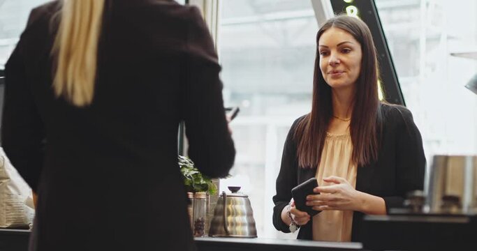 Customer woman paying using NFC technology with phone and credit card, contactless payment with student girl.Pay by phone on electronic payment machine or card reader. E-money at cashless wallet