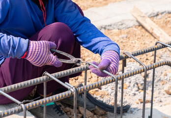 Worker are using pliers to wire bundle to tie the rebar for building foundations