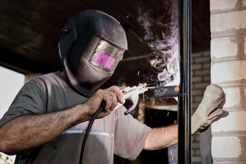 Welder with protective mask welding metal performs welding work