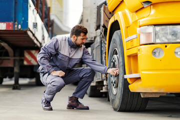 A lorry driver checking on tires before the trip.
