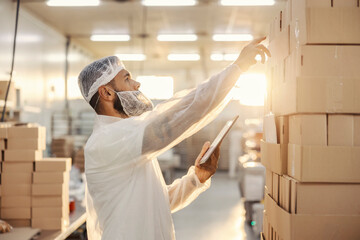 A supervisor with tablet in hands checking on food products.